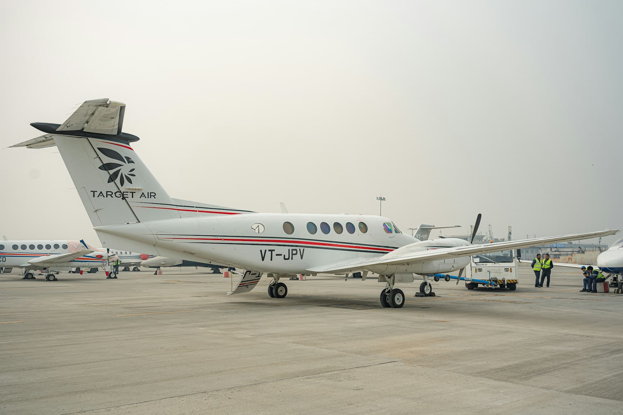 White twin-engine airplane parked on an open airfield, registration toward the camera