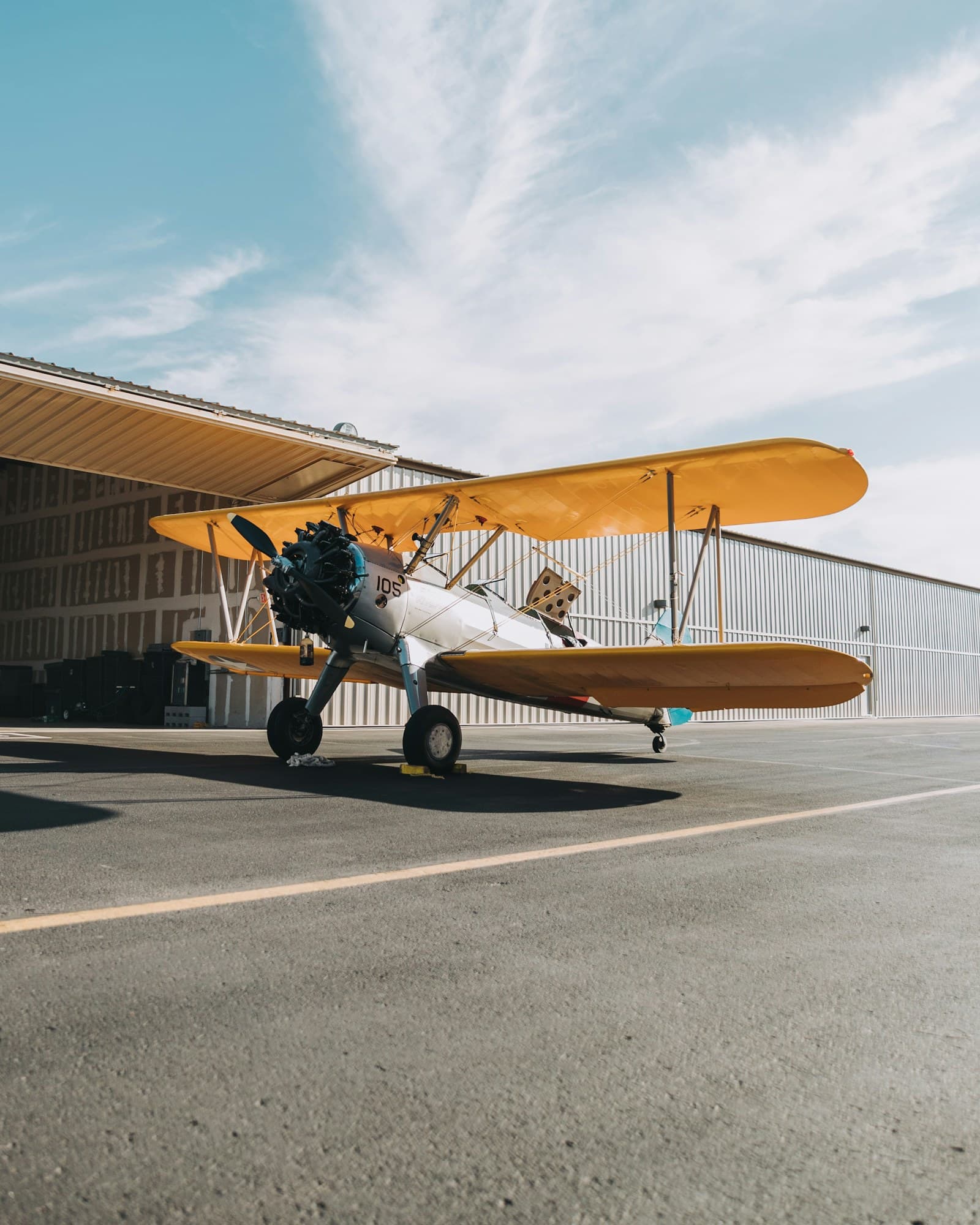 Yellow Stearman biplane outside a hangar — a vintage aircraft whose tail number is part of its history